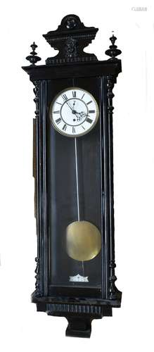 A 19th century ebonised Vienna style wall clock with carved finial of a mask head, above circular