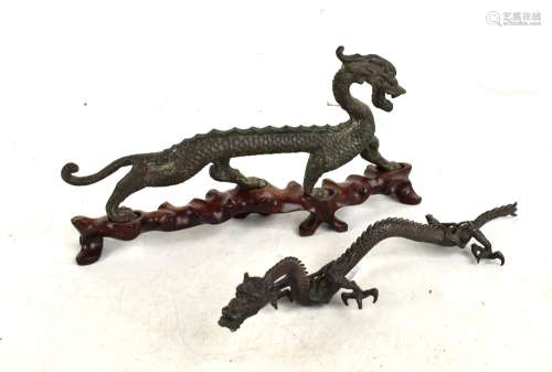 A Chinese cast metal figure of a stylised dragon raised on an associated shaped wooden base,