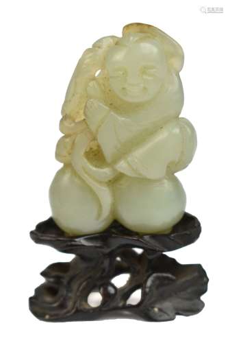 A Chinese jade carving depicting a boy holding two peaches, length 5.5cm, on carved hardwood stand.