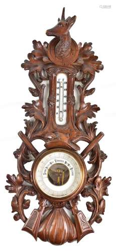 An early 20th century Black Forest barometer, with stag's head finial above carved oak leaves and