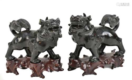A pair of Chinese carved hardstone Kylin on shaped wooden bases, length 12cm, height 12cm.