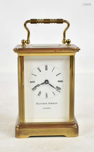 MATTHEW NORMAN; a brass cased carriage clock, the circular enamel dial set with Roman numerals,