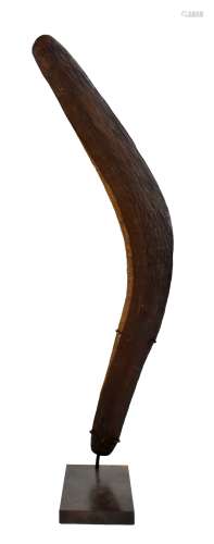An Australian Aboriginal boomerang with adzed decoration, height 53cm, now mounted on a stand.