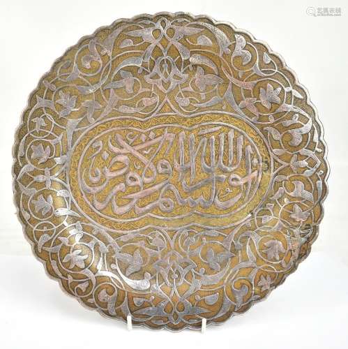 A Middle Eastern late 19th/early 20th century brass and white metal inlaid plate with shaped rim and