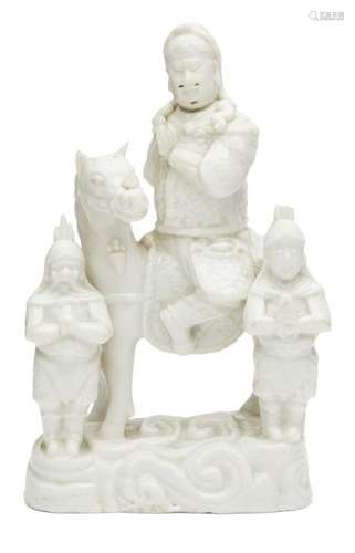 A Chinese blanc de chine figure group, Kangxi period, modelled as Guandi on horseback beside two