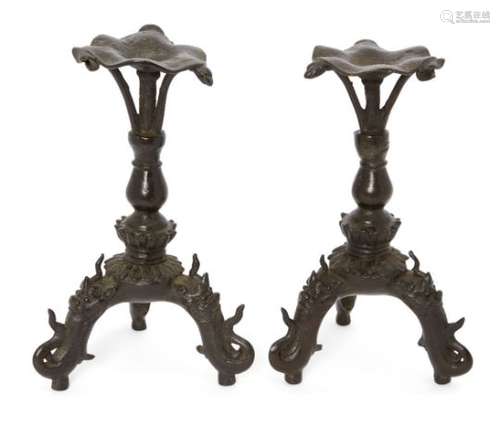 A pair of Chinese bronze tripod candlesticks, Ming dynasty, each raised on three leags cast as a