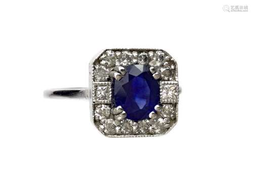 SAPPHIRE AND DIAMOND RING, the octagonal bezel set with a central oval sapphire bordered by round