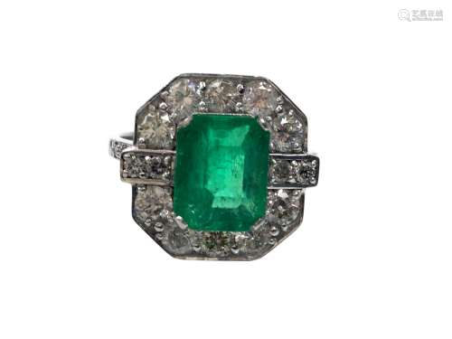 EMERALD AND DIAMOND RING, the octagonal bezel set with central step cut emerald bordered by round