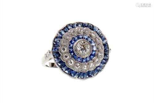 SAPPHIRE AND DIAMOND RING, the central round brilliant cut diamond bordered by calibre cut sapphires