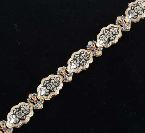 A 14 carat gold bracelet decorated in black enamel with sapphires and rubies.