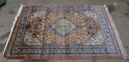 Persian silk burnt-orange ground carpet, with a main blue border, centre of which has concentric