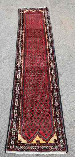 Persian red ground runner with repeating stylised motifs within borders with stylised floral motifs,