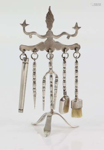 Modern silver miniature fire irons, comprising five pieces hanging on a stand to include a brush,