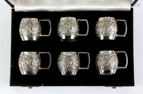 Silver set of six mug form tot cups, each with embossed scrolling floral decoration, stamped