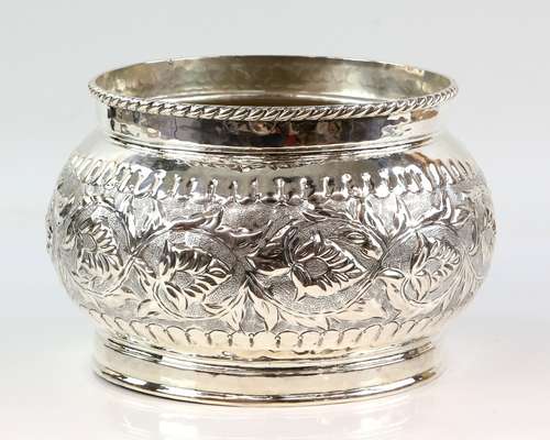 White metal bowl, the body decorated with scrolling flowers and leaves on a stippled ground, stamped