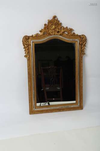 A decorative gilt framed wall mirror with shell and leaf scroll crest above an arched glass,