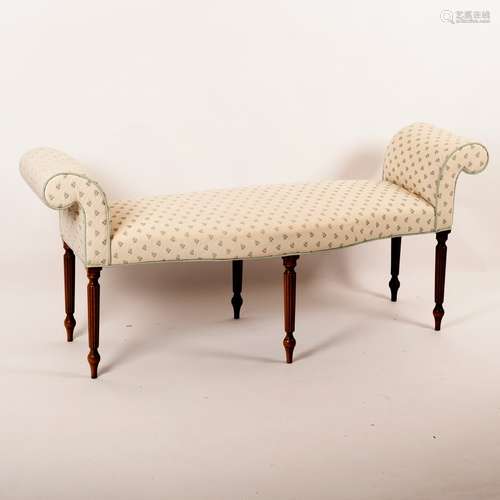 An upholstered window seat with serpentine front, scroll ends and on reeded legs,