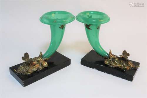 A pair of green glass cornucopia shaped vases issuing from floral sconces with butterfly details,