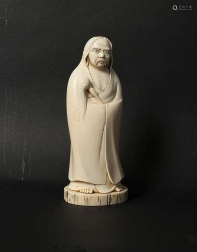A Japanese carved ivory okimono of Daruma, Meiji period, wearing a robe and holding a fly whisk,
