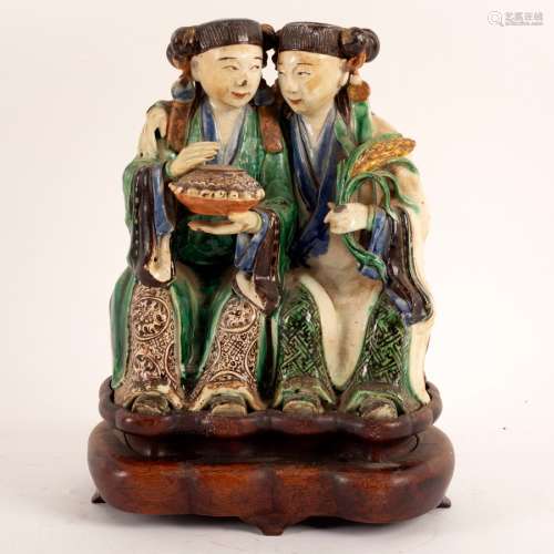 A Chinese 19th Century pottery figure of the Hehe Erxian twins, seated,