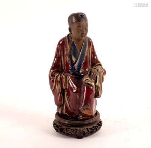 A Chinese stoneware figure of a seated scholar, Guangdong late 19th Century,