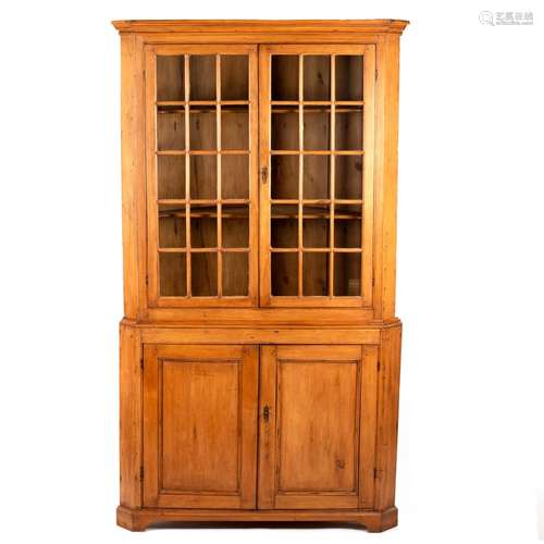 A pine corner cupboard with glazed upper section,