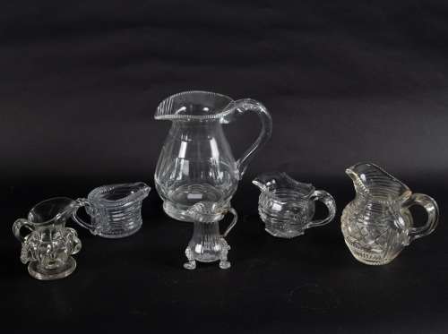 A small 18th Century glass cream jug set on three lion mask and paw feet, with loop handle, 9.