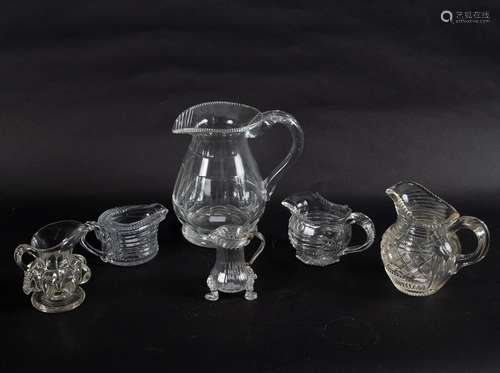 A small 18th Century glass cream jug set on three lion mask and paw feet, with loop handle, 9.