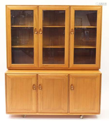 Ercol Windsor light elm display cabinet with three glazed doors enclosing adjustable shelves and