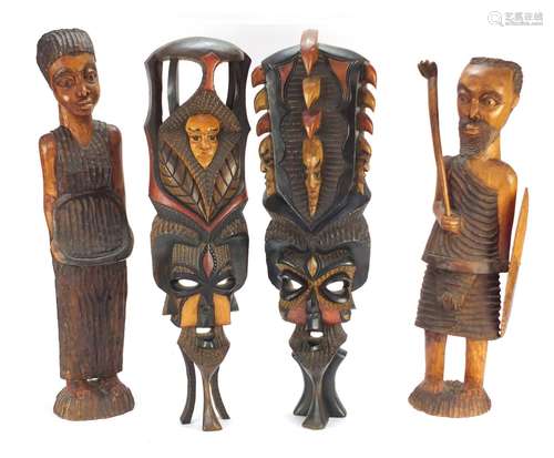 Four tribal wood carvings including a tribesman and two face masks, the largest 60cm high : For