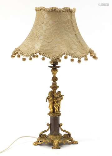 Ornate gilt metal table lamp with silk lined shade, the columned modelled with four nude children