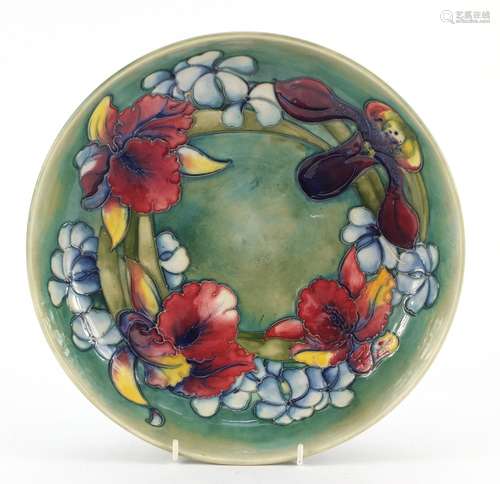 William Moorcroft pottery shallow bowl hand painted in the Orchid pattern onto a green ground,