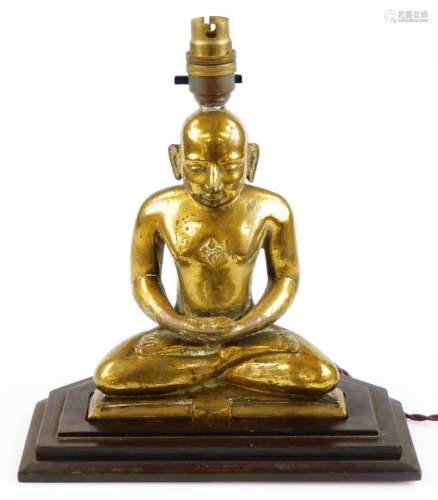 A 19thC gilt metal figure of a seated Buddhistic monk, converted to a lamp, 20cm high plus stepped