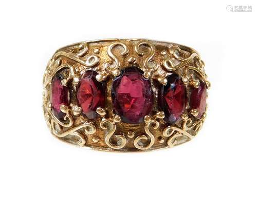 A 9ct gold garnet set dress ring, set with five oval cut garnets, in a scroll design ring frame,