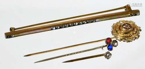 Three stick pins and a bar brooch, comprising a diamond set stick pin with flower type design,