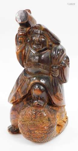 A Japanese wood carving of a Daikoku in flowing robes, holding his mallet, with his foot on a bale