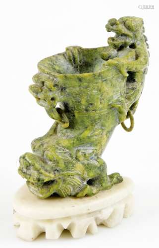 A Chinese mottled green hardstone rhyton cup with carved chilin, fixed white marble finish base