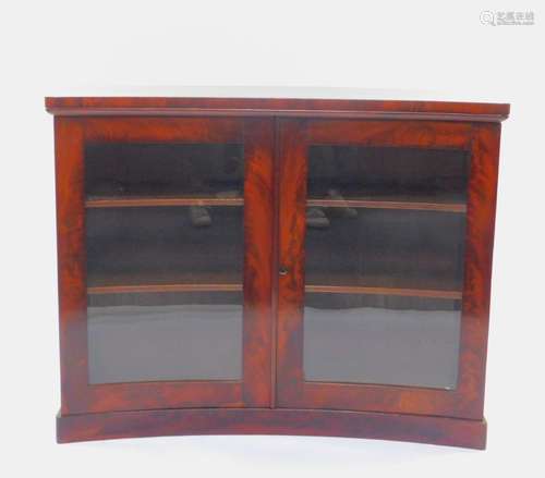 A Regency flame mahogany concave display cabinet, with two glazed doors, opening to reveal two