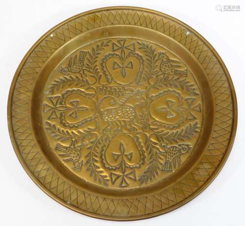 A 19thC continental brass charger, embossed and engraved with heart and cross motifs, birds and