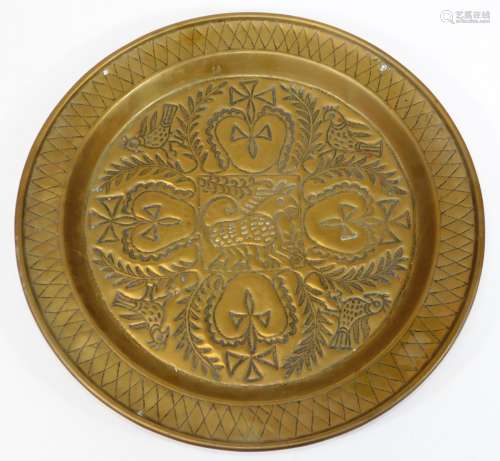 A 19thC continental brass charger, embossed and engraved with heart and cross motifs, birds and