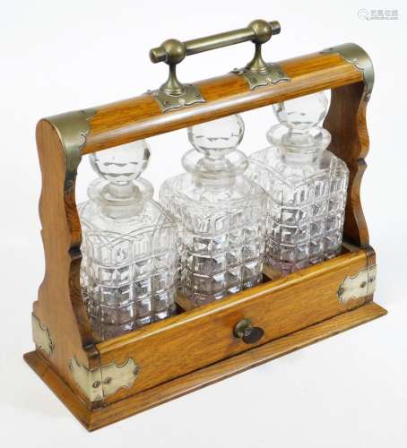 An Edwardian oak framed tantalus, with plated mounts, three moulded and cut finish glass decanters