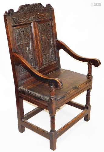 A principally late 17thC oak Wainscot chair, with a scroll cresting rail, raised above two panels of