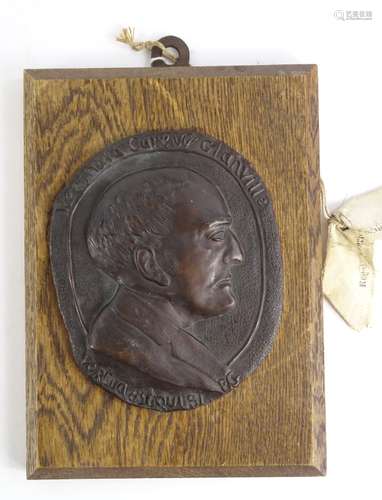 •Attributed to Eric Gill (1882-1940). Reginald Caren Clanville, oval bronze plaque on oak mount,