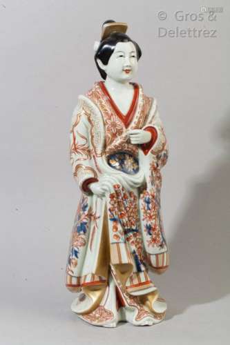 Sujet en porcelaine d'Imari représentant une courtisane en pieds, vêtue d'un riche kimono à décor floral bleu, corail et or.