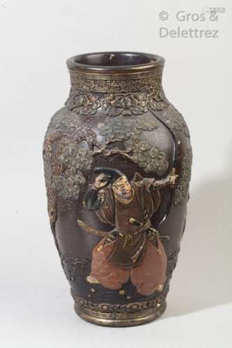 Vase balustre en grès émaillé et décoré en léger relief d'une scène figurant deux guerriers chassant un singe dans une forêt de pins. Le col souligné d'une frise de grecques.