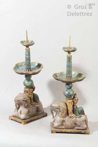 Chine, fin de la période Qing  Paire de piques-cierges en bronze doré et repoussé, émaux cloisonnés polychrome, reprenant la forme de deux béliers agenouillés blancs sur lesquels se trouve un jeune servant adossé à une colonne.  H. 47 cm                                                                                                                                                                                                                                                                                                                         估价            2 000 - 3 000 EUR                                                                                                                                                                * 不计佣金。