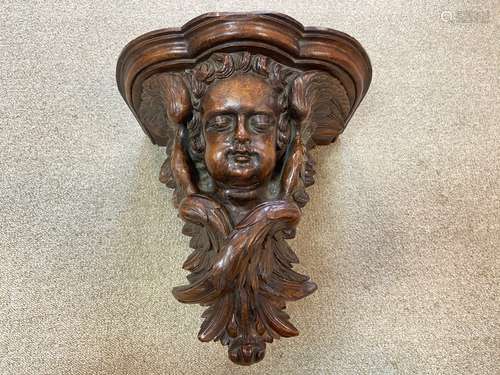 A carved walnut cherub mask wall bracket, probably 18th century,