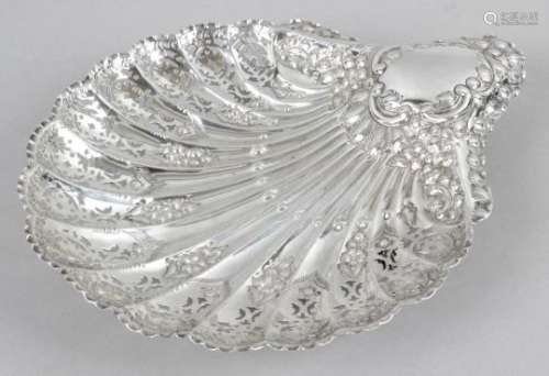 A late Victorian silver dish in the form of a scallop shell and raised on three reeded ball feet,