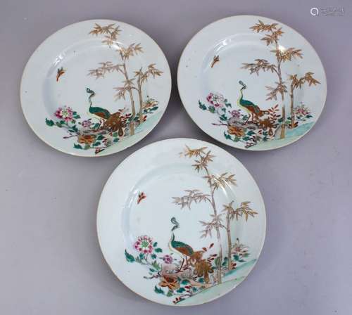 THREE 18TH CENTURY CHINESE FAMILLE ROSE PLATES, decorated with peacock amongst landscapes, 23cm.