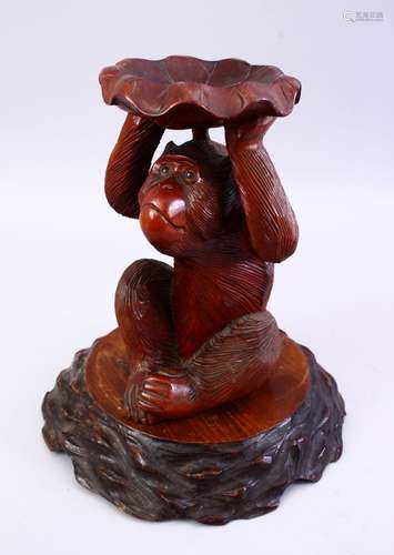 A GOOD JAPANESE MEIJI PERIOD CARVED WOOD FIGURE OF A MONKEY, holding a lotus above his head,